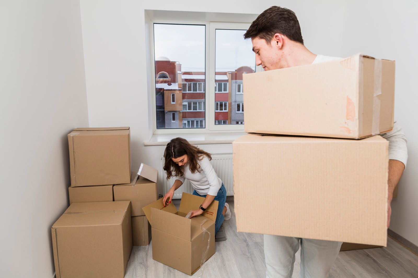 man-carrying-cardboard-boxes-looking-her-girlfriend-unpacking-box-new-home